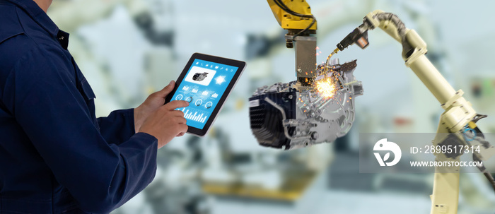 iot industry 4.0 concept,industrial engineer using software (augmented, virtual reality) in tablet to monitoring machine in real time.Smart factory use Automation robot arm in automotive manufacturing