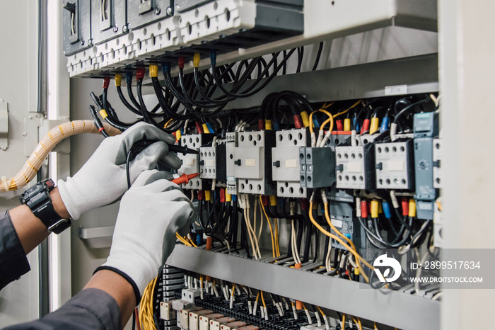 Electrician engineer tests electrical installations and wires on relay protection system.