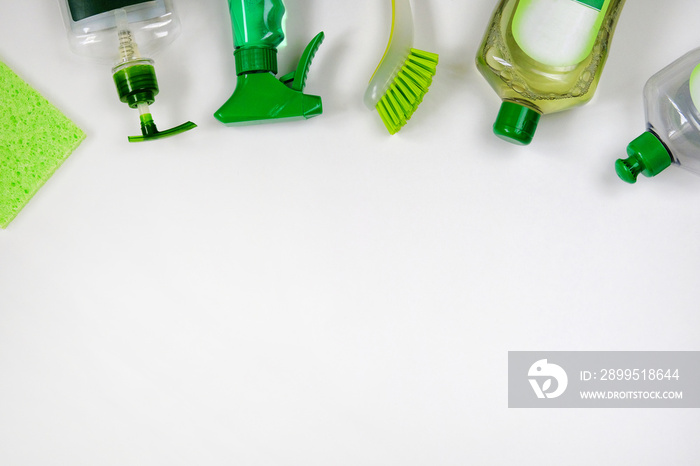 Detergents in plastic bottles. Сleaning accessories. Flat lay of green and white cleaning supplies on white background. Top view. Close up.