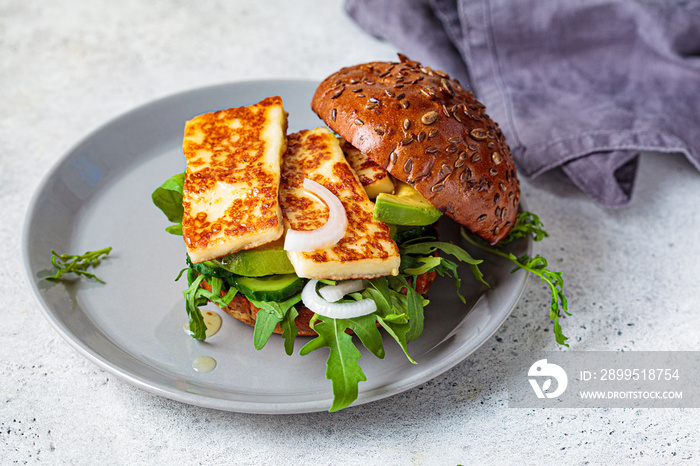 Grilled halloumi burger with slices of avocado and arugula. Vegetarian food concept.