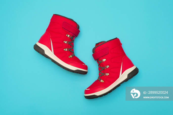 Kids or teenage pink winter boots isolated on blue background. Winter boots for girls