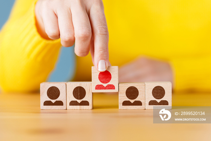 Person icon on wooden cube with hand picked different from the crowd