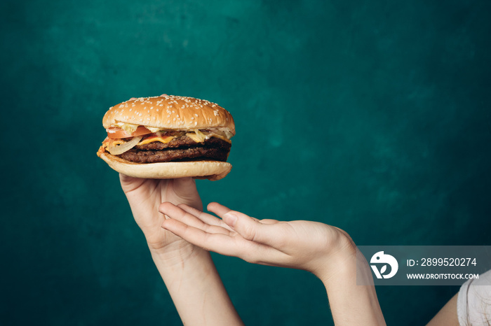 hamburger in hands close-up fast food green background