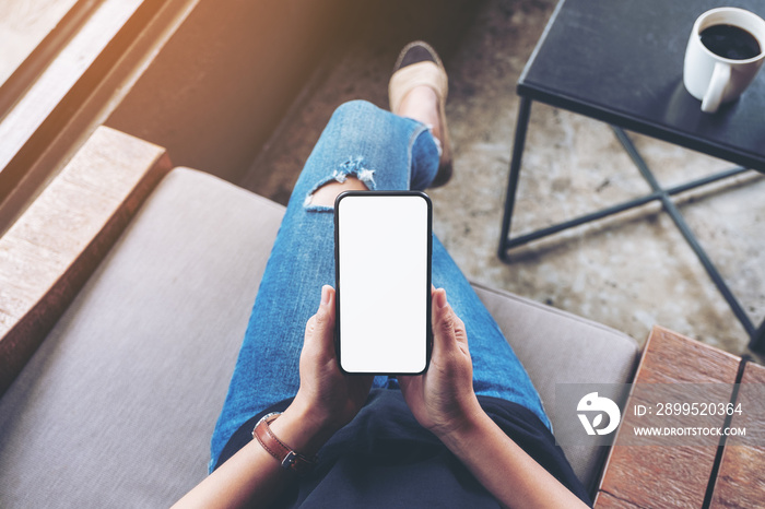 Top view mockup image of woman holding black mobile phone with blank screen while sitting in cafe