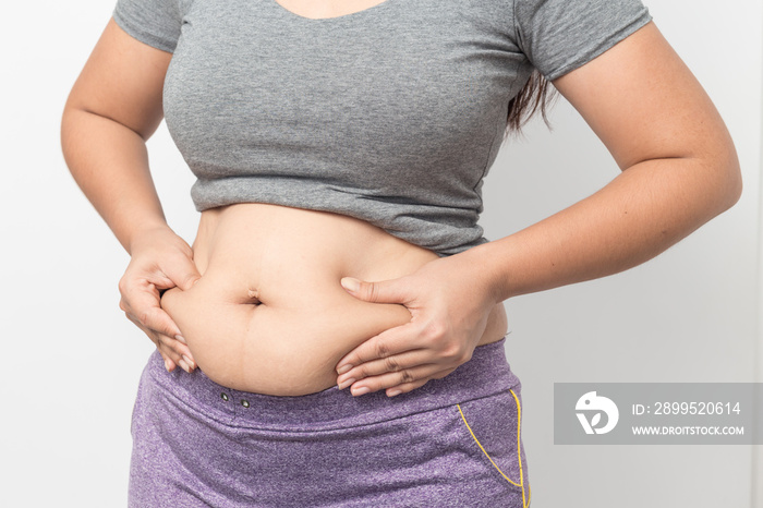 Overweight woman hand pinching excessive belly fat on gray background, Healthy concept