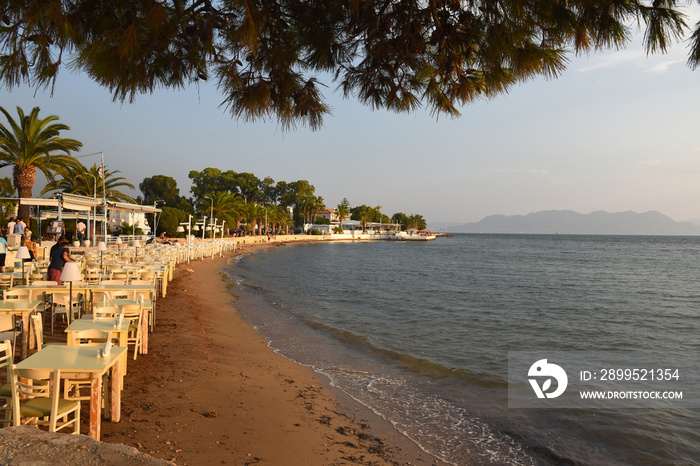 tables set for dinner on the beach at sunset over the sea in Aegina in Greece