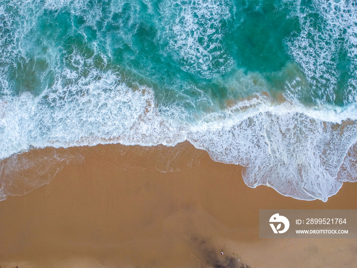 Sand beach aerial, top view of a beautiful sandy beach aerial shot with the blue waves rolling into the shore