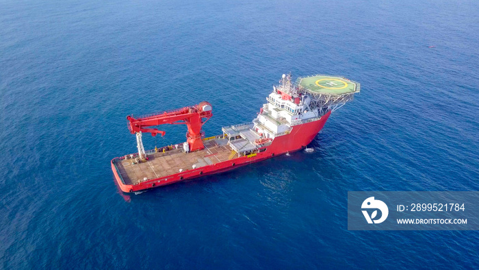 Aerial image of a Medium size red Offshore supply ship with a Helipad and a large crane