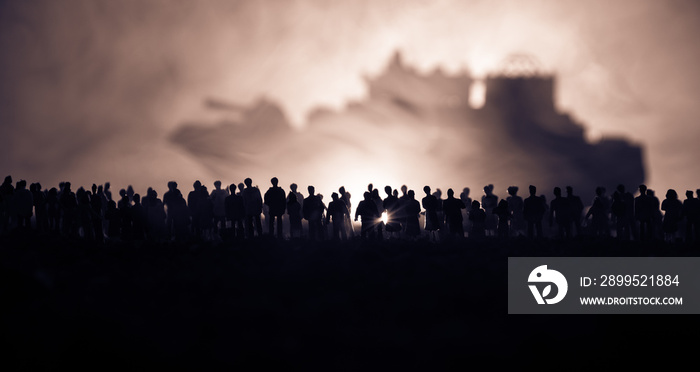 Silhouettes of a crowd standing at blurred military war ship on foggy background. Selective focus. Passengers try to escape.