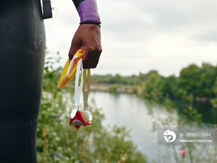 Woman holding swimming goggles by river