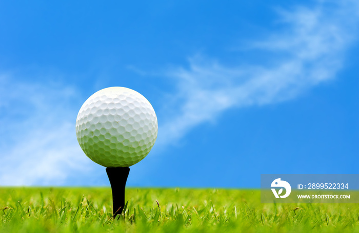 Golf ball on tee ready to shot on green grass over blue sky