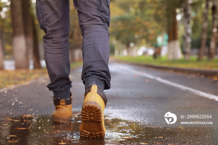 Autumn concept. Pedestrian feet on the road. Autumn leaves on the footpath.