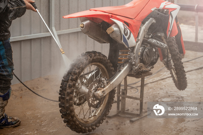 Cross-bike washing after the competition. Washing dirty wheel of motorcycle after the race. Detail of the motocross bike. Extreme sport.