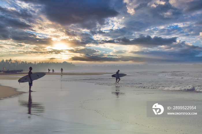 Surfer on the beach in Hikkaduwa at sunset with clouds. Peacefull mood and freedome.