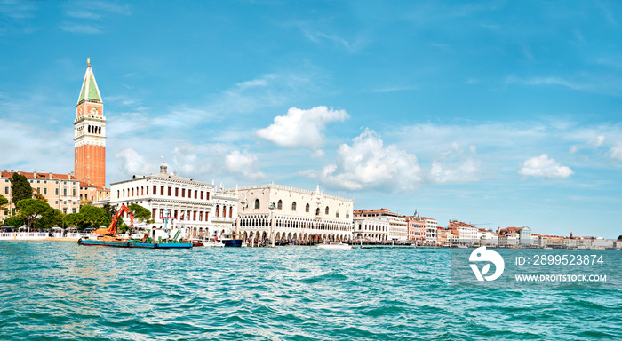 Doge’s palace and Campanile on Piazza di San Marco, Venice, Italy. View from the passing ship with water in front. Panoramic banner image with blue sky and feather clouds.