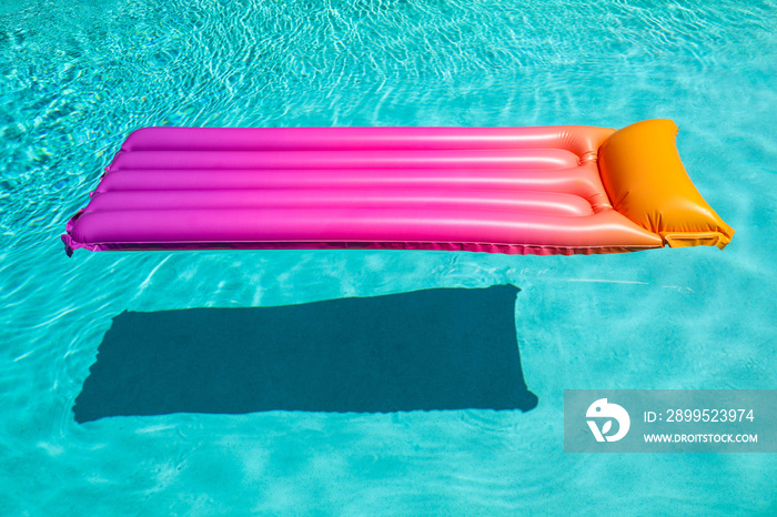 Bright pink inflatable sun bed floating in turquoise pool