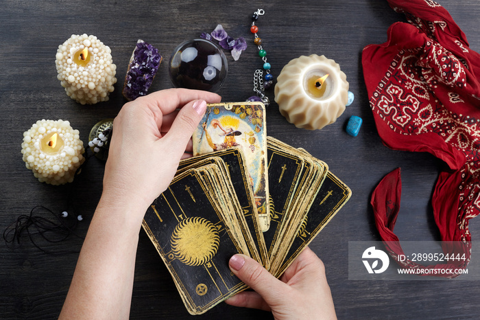 Fortune teller female hands and tarot cards on dark wooden table. Divination concept.