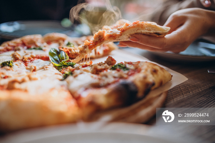 Three firends together eating pizza in a cafe