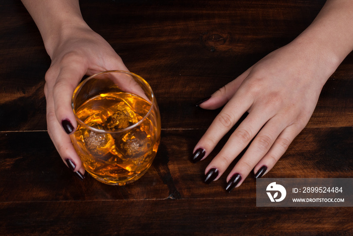 woman’s hands with a glass with whiskey