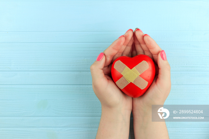 red heart glued with a band-aid in female hands