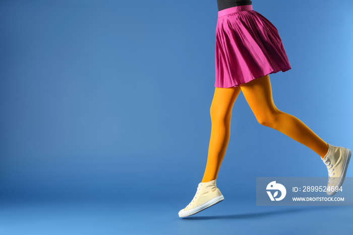 Legs of beautiful young woman wearing tights and skirt on color background