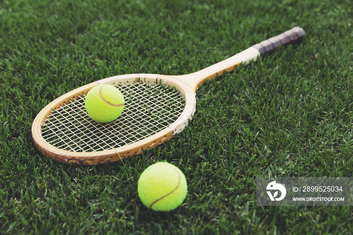 vintage wooden tennis racket on grass with balls