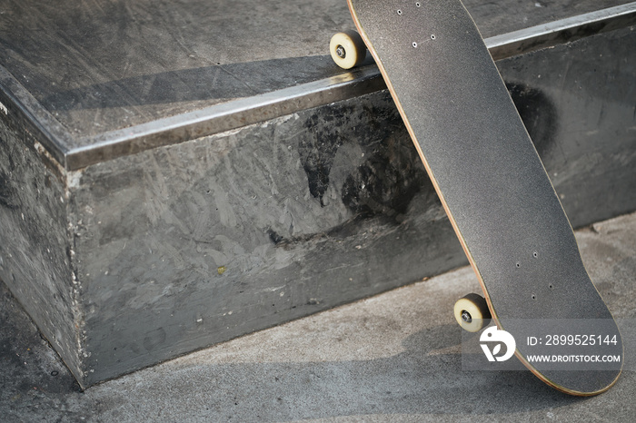 View of black skateboard in concrete skatepark on warm day