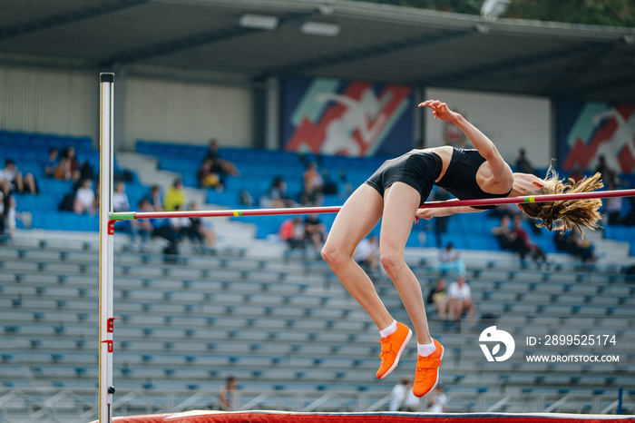 female athlete high jump on background fan stands