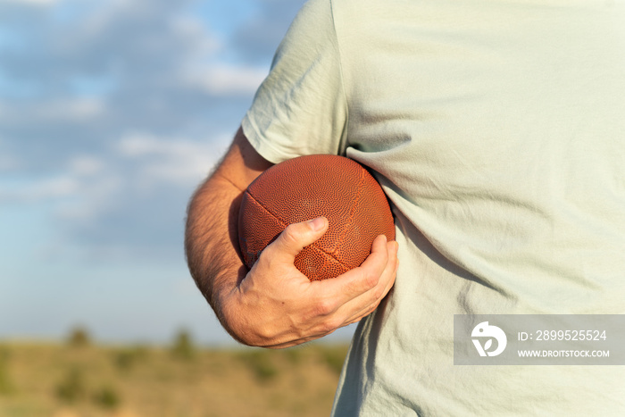 Horizontal view of a male hand holding a rugby ball.