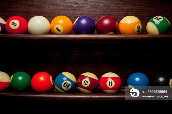 Balls for pool billiards on the shelf / billiard balls for American billiards / balls for Russian billiards / colored or white balls for billiards on a wooden background. Close-up photo. Soft focus.