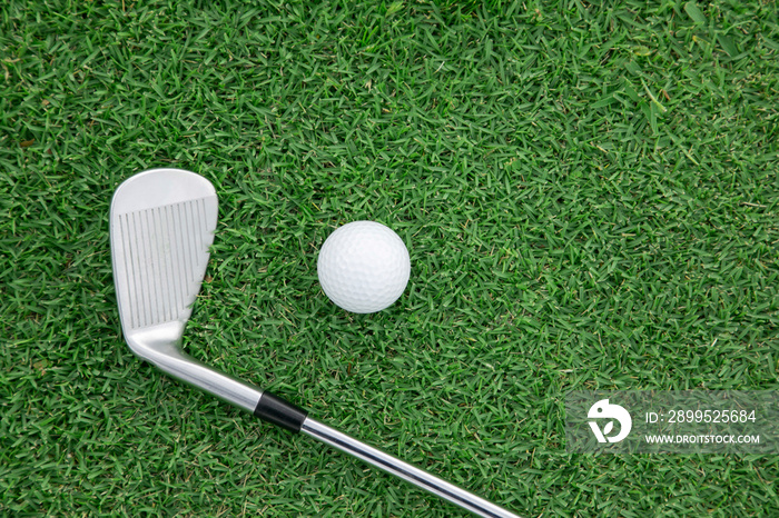 Top view of iron golf club and golf ball on the green grass