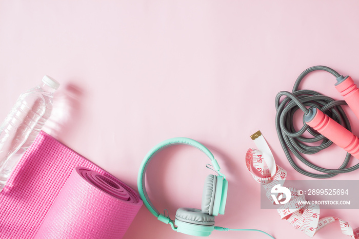 Healthy flat lay with sport and fitness equipments and mint color headphones on pink color background