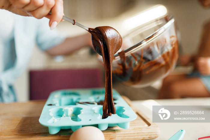 Mother fill melted chocolate in the baking form