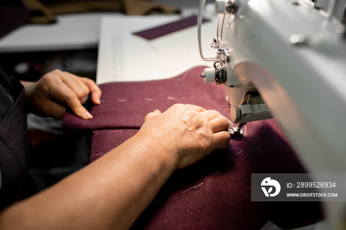 Women’s hands sew pieces of fabric on a sewing machine close-up. horizontal frame