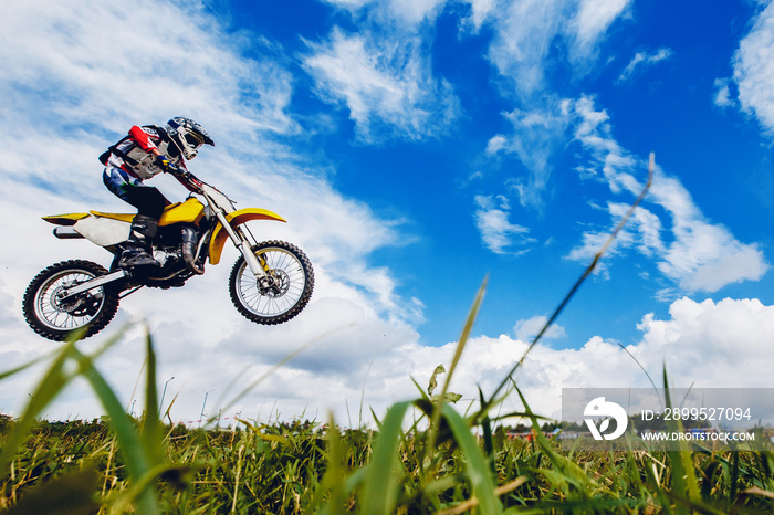 racer on a motorcycle participates in motocross cross-country in flight, jumps and takes off on a springboard against the sky. Concept active extreme rest.