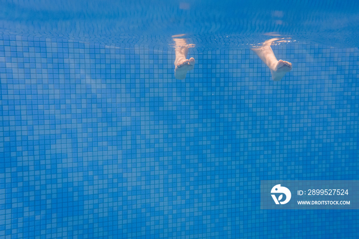 Feet of people moving under the water in the pool. Children legs. Summer. Funny underwater legs in swimming pool, underwater view of women or kids, vacation and sport concept.