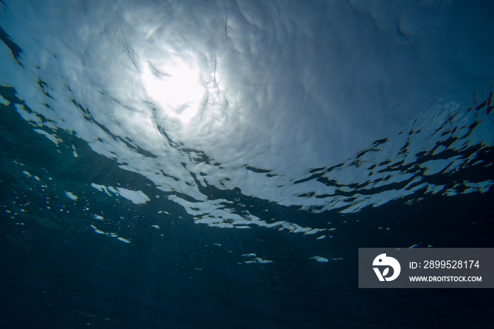 underwater image with crystal clear sea and view of sun rays penetrating the navy blue