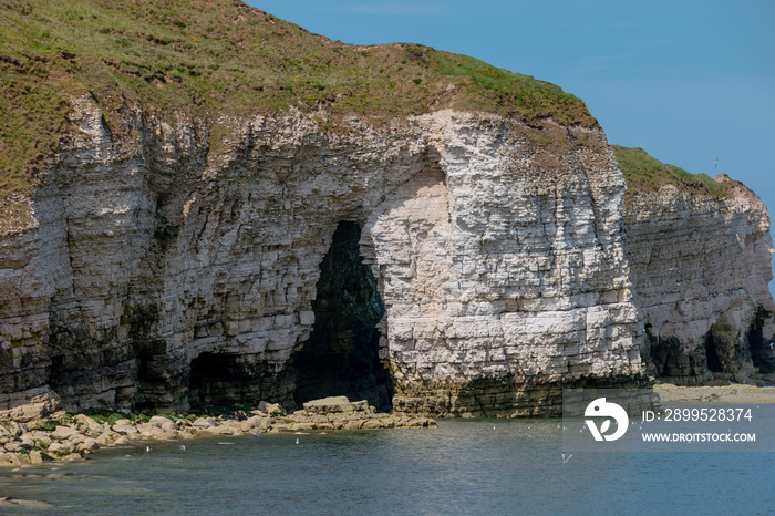 Landscape of layered white chalk cliffs showing wave erosion into the north sea at Flamborough