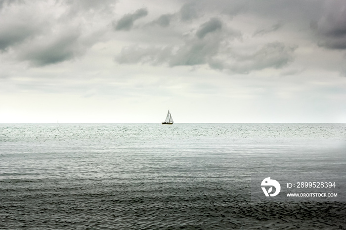 Single lone boat in Deep sea and heavy overcast clouds