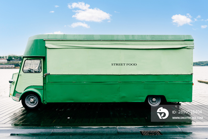 Green retro food truck parked on promenade by the sea