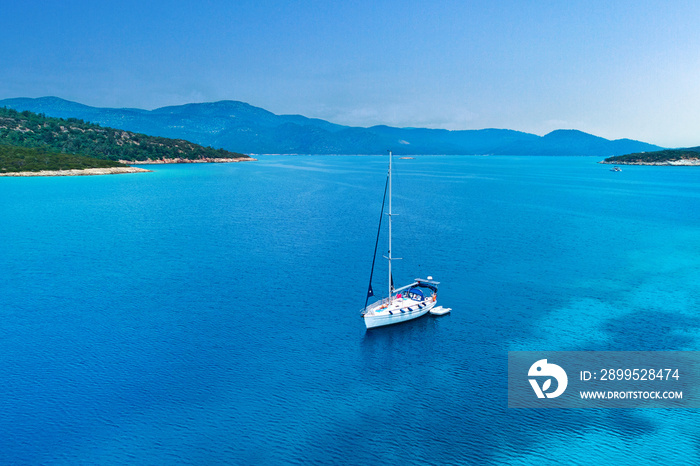 Drone photo aerial view of white sailboat in azure turquoise sea bay