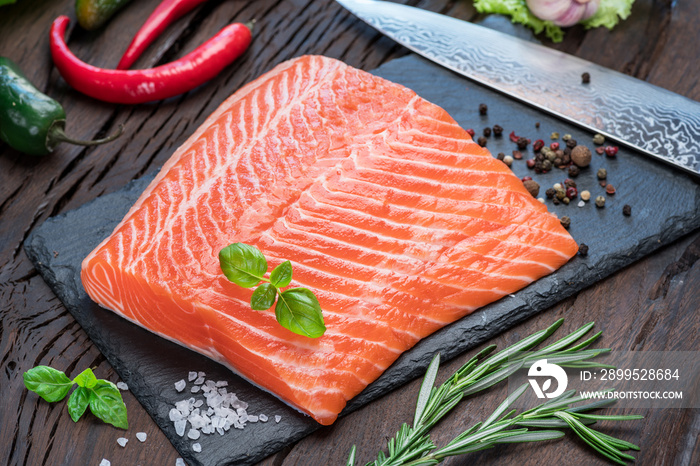 Fresh salmon fillet on black cutting board.