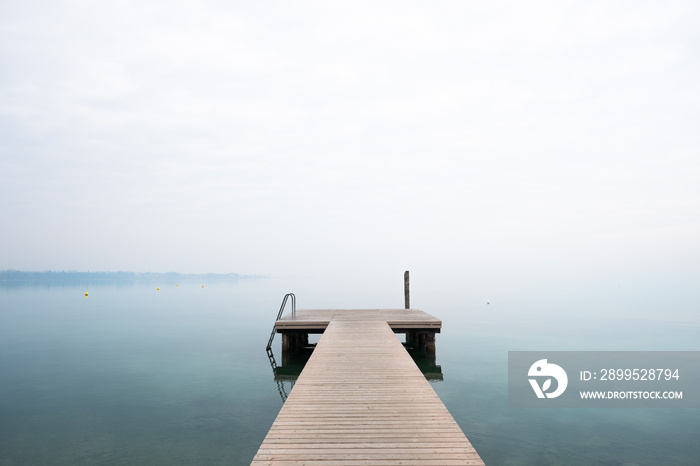 Pontile vuoto sul lago in una giornata nebbiosa