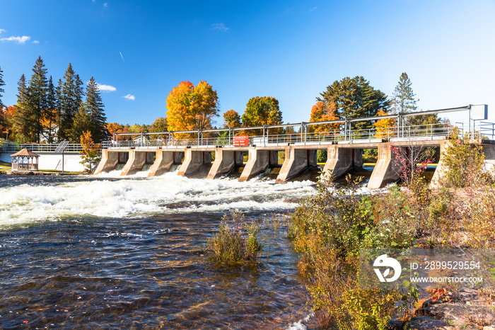 Small dam on a river on a clear autumn day. Autumn colours.