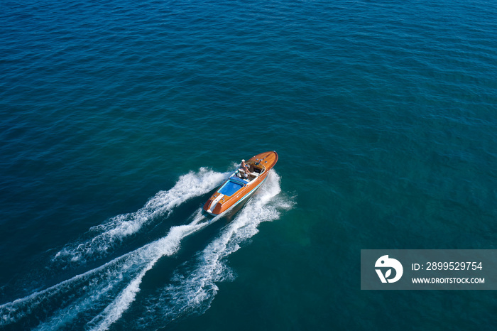 Riva Aquarama Classic in motion on the water aerial view. Aquarama special top view. Large classic Italian boat with two men moving fast on the water.