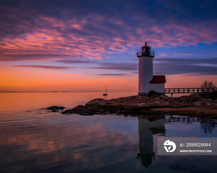 Sunset reflections at Annisquam Lighthouse with sail boat - Gloucester, Massachusetts.