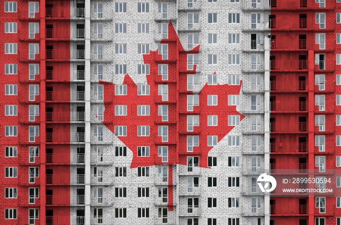 Canada flag depicted in paint colors on multi-storey residental building under construction. Textured banner on brick wall background