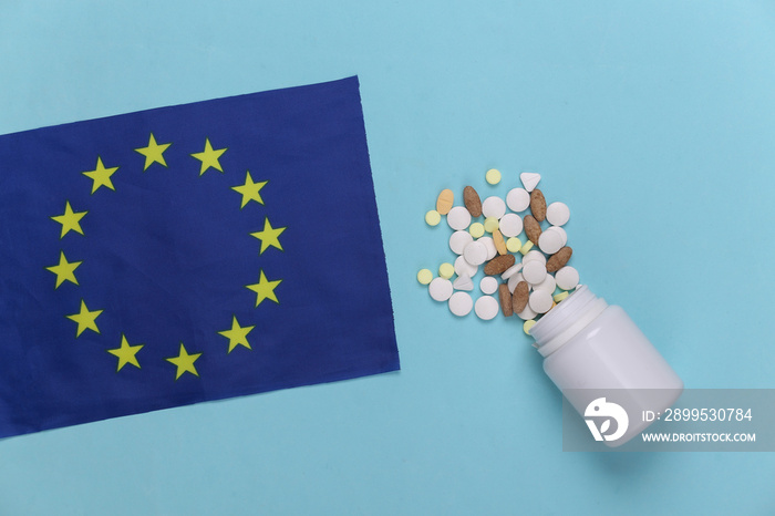 European flag and a bottle of pills on a blue background. Top view