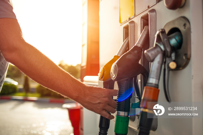 Man hand holding a fuel pump at a station. Detail of a hand holding a fuel pump at a station. Colorful Petrol pump filling nozzles, Gas station in a service. Detail of a hand holding a fuel pump