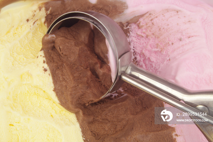 Strawberry, vanilla and chocolate ice cream with metallic scoop close up